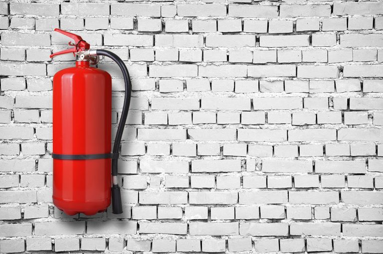 fire extinguisher on white brick wall