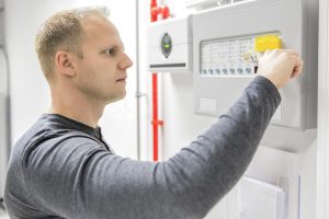 Engineer or technician looking at alarm panel for aspirating fire detection system in datacenter. 