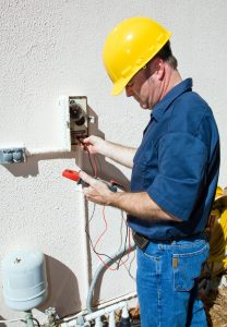 Electrician repairing a sprinkler pump, testing to see if it's receiving power. Focus on model. Model is a licensed electrician, working in compliance with national code and safety regulations.